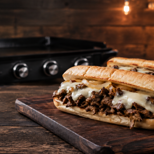 Griddle Philly cheesesteaks recipe promo card featuring shaved beef, caramelized onions, melted cheese, and cooking details.