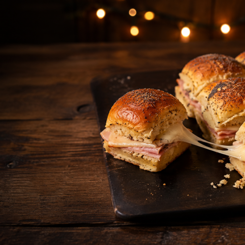 Ham and Swiss Hawaiian roll sliders topped with buttery poppy seeds and filled with thinly sliced ham and melted Swiss cheese.
